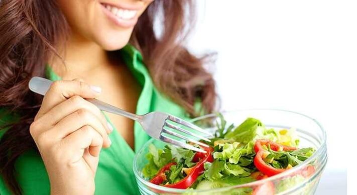 Vajza që ha sallatë perimesh në një dietë proteinike
